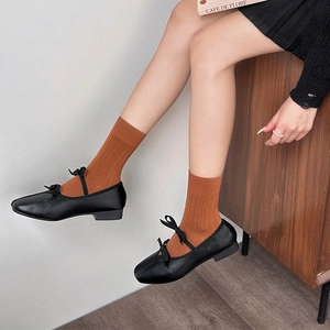 Vue détaillée des babies noires à double nœud avec des chaussettes orange à côtes
