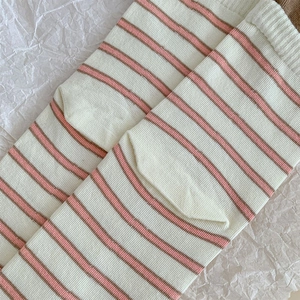 Detail of knit crew socks featuring soft beige and pink horizontal striped texture