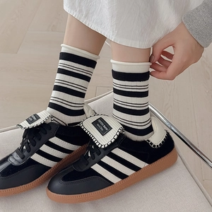 Close-up of black and white striped socks paired with retro leather sneakers on a model