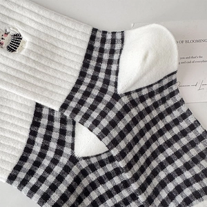 Detailed close-up of white ribbed cotton socks with cat embroidery and gingham pattern