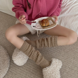 Detail of beige ribbed knit leg warmers with cozy textured yarn in home setting