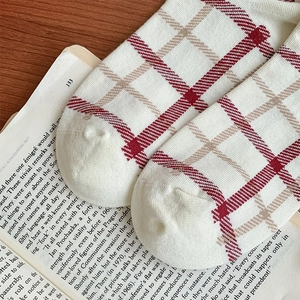 Close-up of red and beige plaid cotton socks laid on an open vintage English book