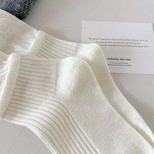 Macro detail of white ribbed knit ballet socks with soft texture for feminine styling