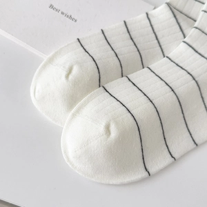 Close-up of white cotton ribbed socks featuring fine black stripes and soft knit texture