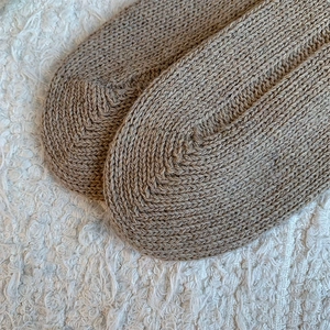 Close-up of knit texture and rounded toe design on cream white thigh high socks