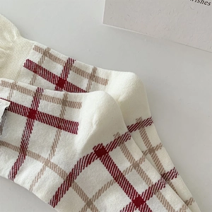 Close-up of red plaid cotton mid-calf socks with detailed knit texture on white background