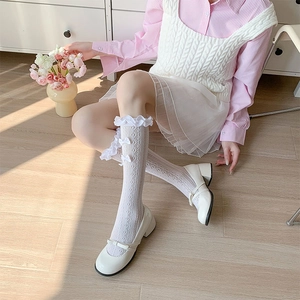 Close-up of white Lolita lace socks with bow ties and mesh knit texture on wooden floor