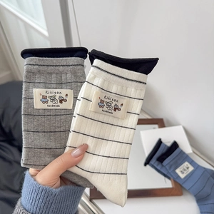 Close-up of striped crew socks featuring a cute bear patch and handmade label detail