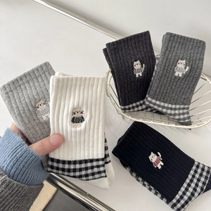 Detail of soft knit mid-calf socks with cute cat embroidery and checkered patterns