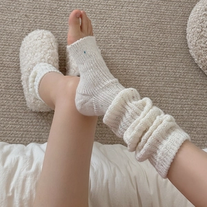 Detailed knit texture of cream white leg warmers with colorful dots and ribbed cuffs