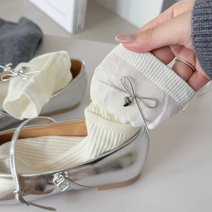 Detail of white knit socks with silver ribbon bows and metallic heart charms