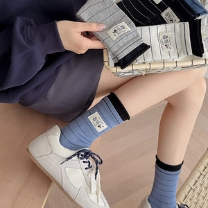Detailed view of striped crew socks with a cute bear tag and rib knit cuffs design