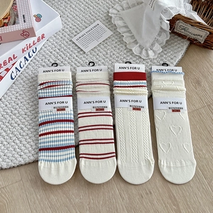 Detail of four retro striped and heart textured crew socks with branded packaging labels