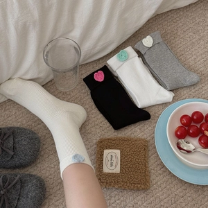 Detail of knit crew socks with colorful 3D crochet heart patches and ribbed texture