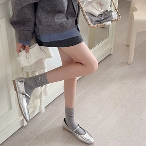 Detail of grey ribbed ballet socks featuring silver bow pendants and Mary Jane shoes
