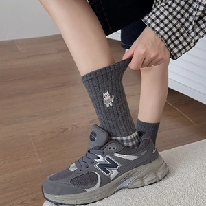 Close-up of ribbed dark grey cotton socks featuring cute cartoon cat embroidery detail