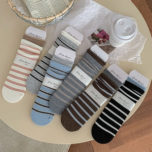 Set of six colorful striped crew socks with ribbed cuffs arranged on a minimalist table