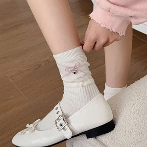 Detail of white ribbed mid-tube socks featuring pink ribbon bows and heart metal charms