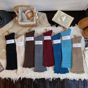 Detailed knit texture and scalloped edges of colorful leg warmers in various shades