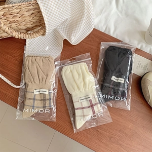 Detailed view of three pairs of vintage plaid knit socks in branded packaging on wood