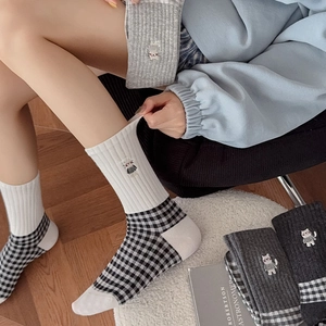 Close-up of retro black and white checkered socks with cute cat embroidery details