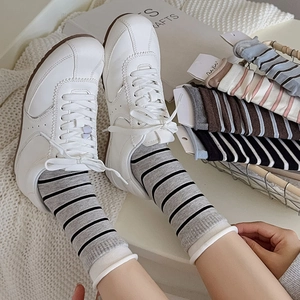 Detail of striped cotton crew socks in neutral tones styled with white sneakers