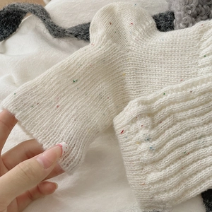 Detail of white chunky knit leg warmers with colorful speckled yarn texture