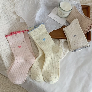 Détail de chaussettes en fil moucheté avec broderie cœur et bords ondulés doux