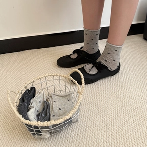Detail of grey bow socks with rolled cuffs paired with black Mary Jane shoes