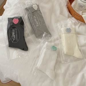 Detail of four pairs of ribbed mid-calf socks with crochet hearts in individual zipper bags