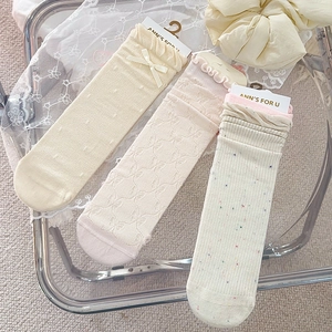 Detailansicht von beigen Schleifensocken und gepunkteten Wadensocken auf Spitze