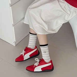 Close-up of red low-top sneakers paired with black and white striped cotton crew socks