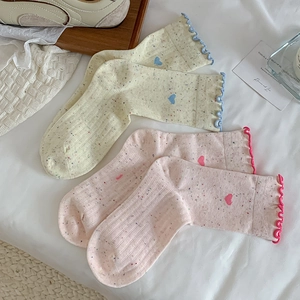 Détail de chaussettes à motif cœur, bordure à volants et maille mouchetée de pois colorés