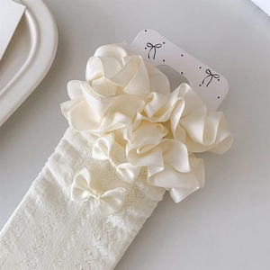 Close-up of cream white Lolita socks featuring ruffled satin lace and a small bow