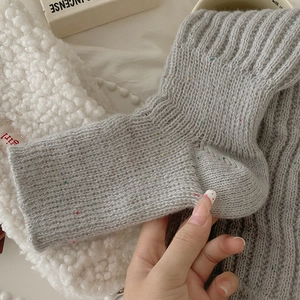 Close-up of thick grey knit leg warmer featuring vibrant colorful speckled yarn details