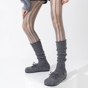Close-up of dark grey knitted leg warmers with hollow patterns and matching bow slippers