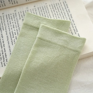 Close-up of light green knit cotton socks with ribbed cuffs on an open book page