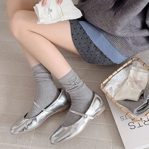 Gray ribbed crew socks with bow tie and heart pendant worn with silver Mary Janes