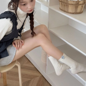 Detail of off-white ribbed cotton mid-calf socks featuring a cute blue knitted heart