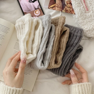 Detailed knit texture of thick ribbed leg warmers in neutral cream, grey and oat tones
