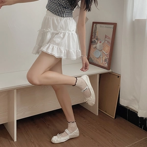 Detail of white tiered skirt with delicate bows and lace edges in a cozy room setting