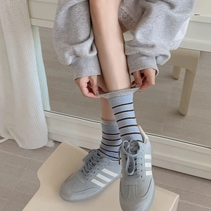 Blue and grey striped crew socks for women styled with retro grey suede sneakers