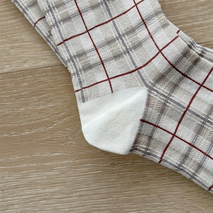 Detail of red and gray plaid knit socks showing heel construction and cotton fabric texture