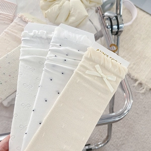 Detailansicht der beigen Schleifenakzente und feinen Polka-Dot-Jacquardmuster der Socken