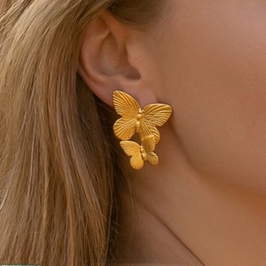 Detailed macro view of matte gold double butterfly stud earrings with velvet texture finish