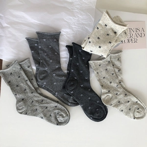 Close-up of ribbed knit cotton socks featuring delicate bow patterns and rolled edges