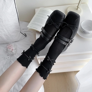 Detail of black Mary Jane shoes with double buckles and bow-accented knit socks