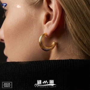 Close-up of golden C-shaped textured earrings worn with a sleek minimalist aesthetic