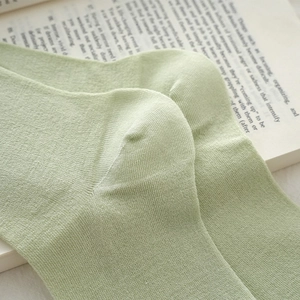 Close-up of the fine knit texture and heel stitching on a pale green cotton crew sock