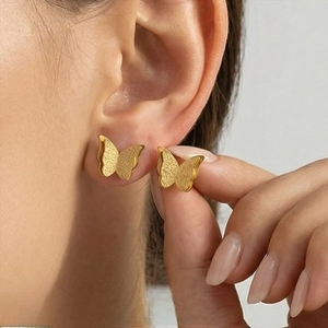 Macro view of matte golden butterfly stud earrings with textured wing details